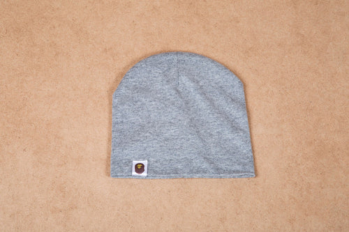 Gray beanie hat with a small logo patch on neutral background