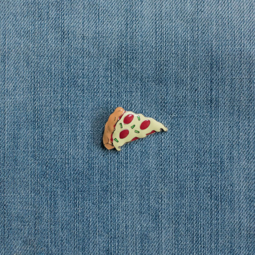 Pizza slice enamel pin on blue denim fabric background