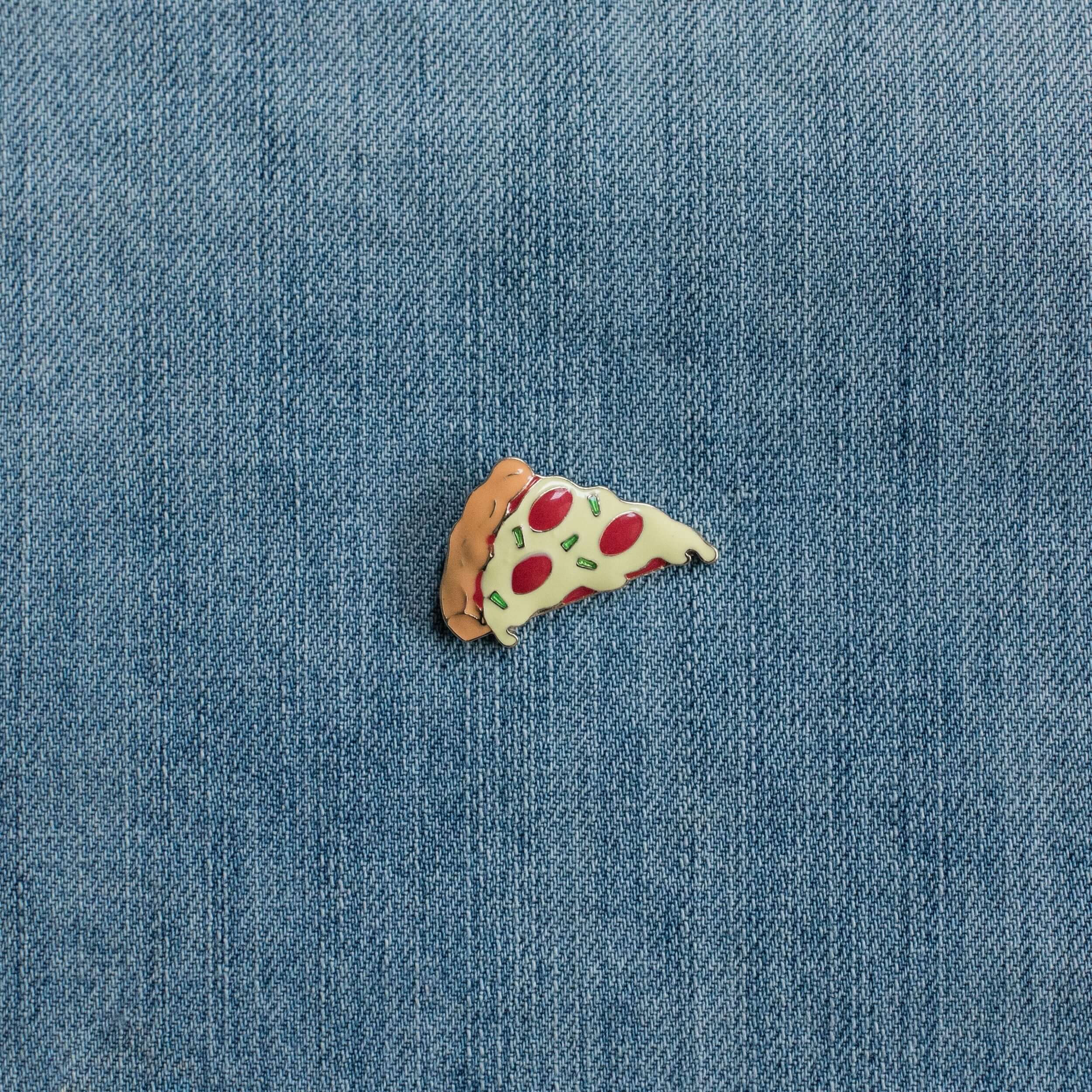 Pizza slice enamel pin on blue denim fabric background