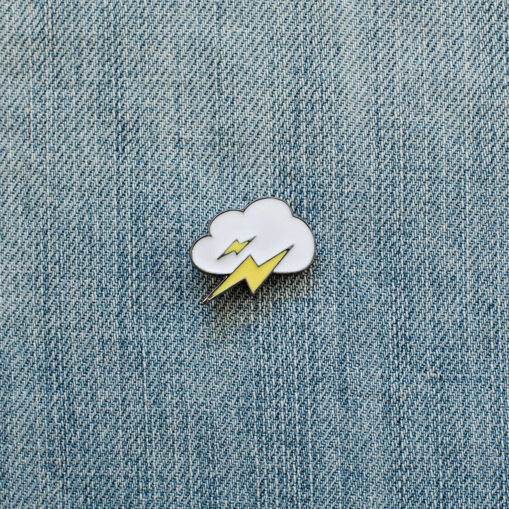 cloud and lightning enamel pin on blue denim fabric