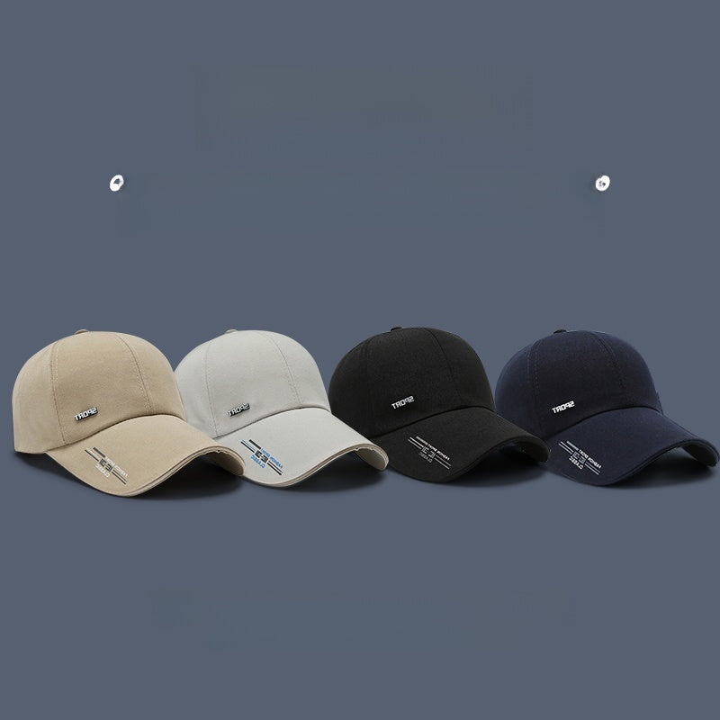 Set of four baseball caps in beige, gray, black, and navy on a solid blue background