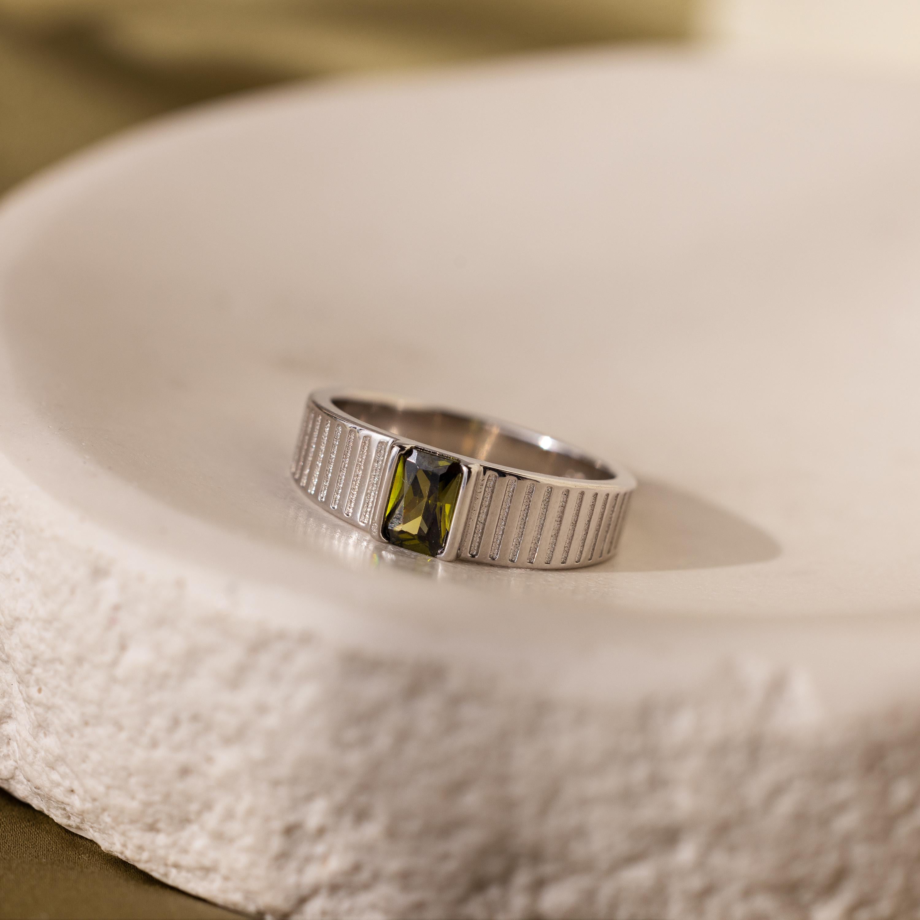 Silver ring with rectangular green gemstone and vertical grooved band on round stone plate