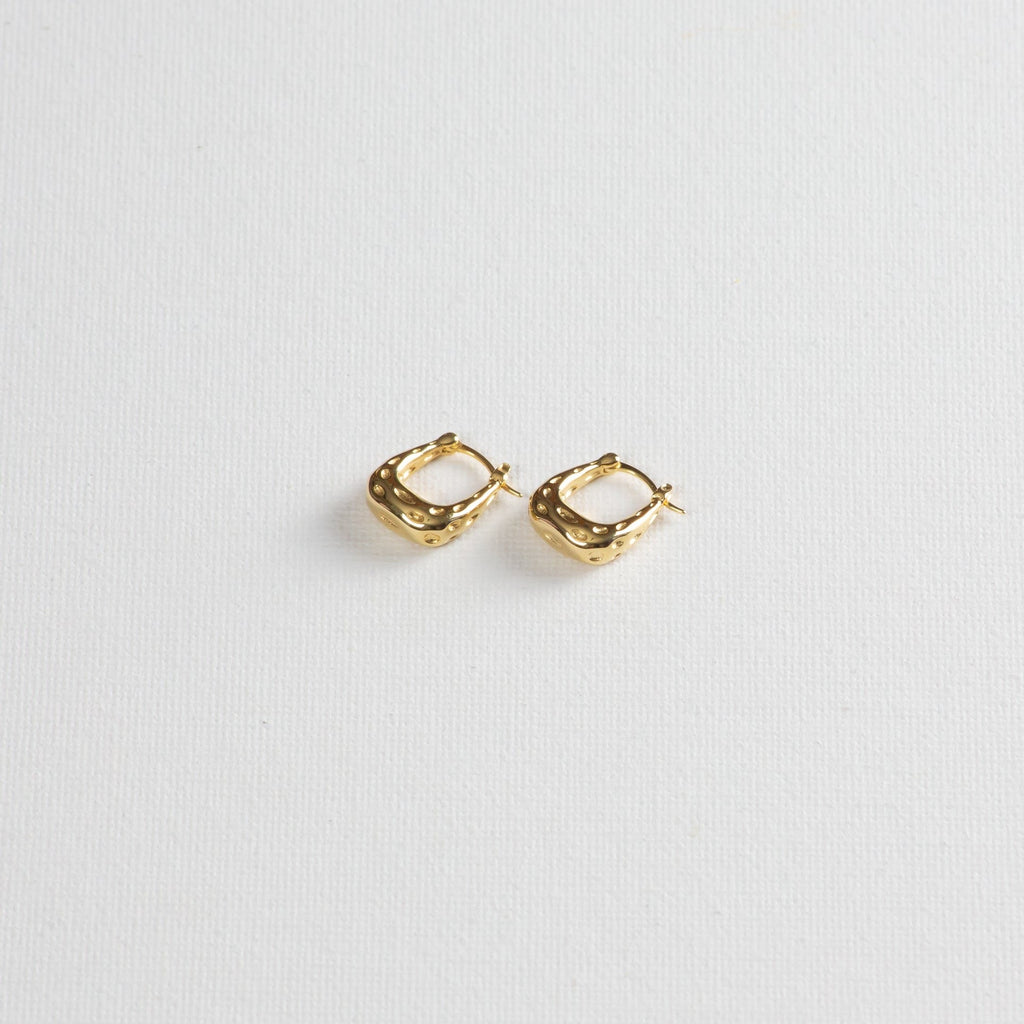 Gold textured hoop earrings on white background