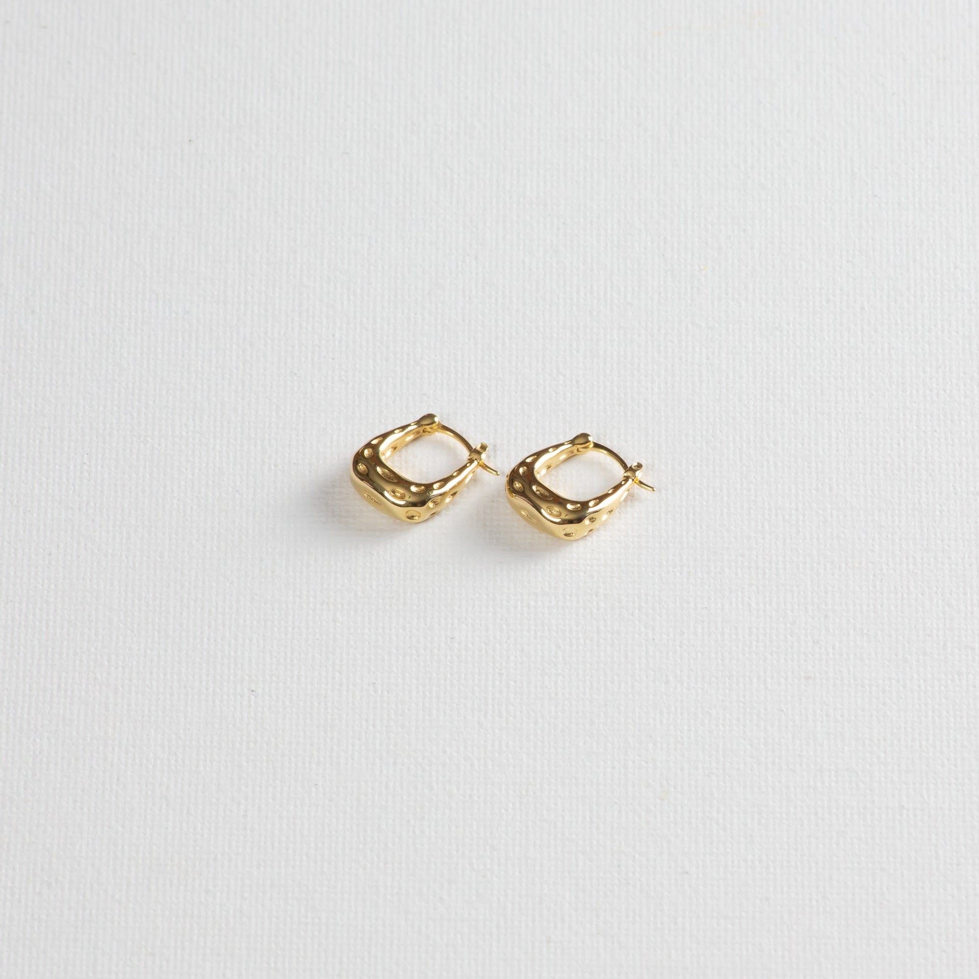 Gold textured hoop earrings on white background