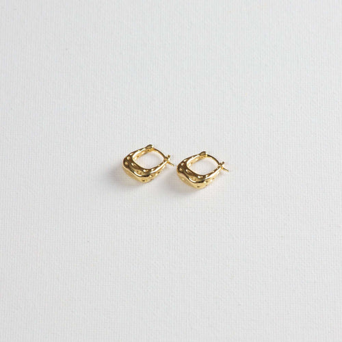 Gold textured hoop earrings on white background