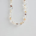 Multi-colored freshwater pearl and gold bead necklace on white background
