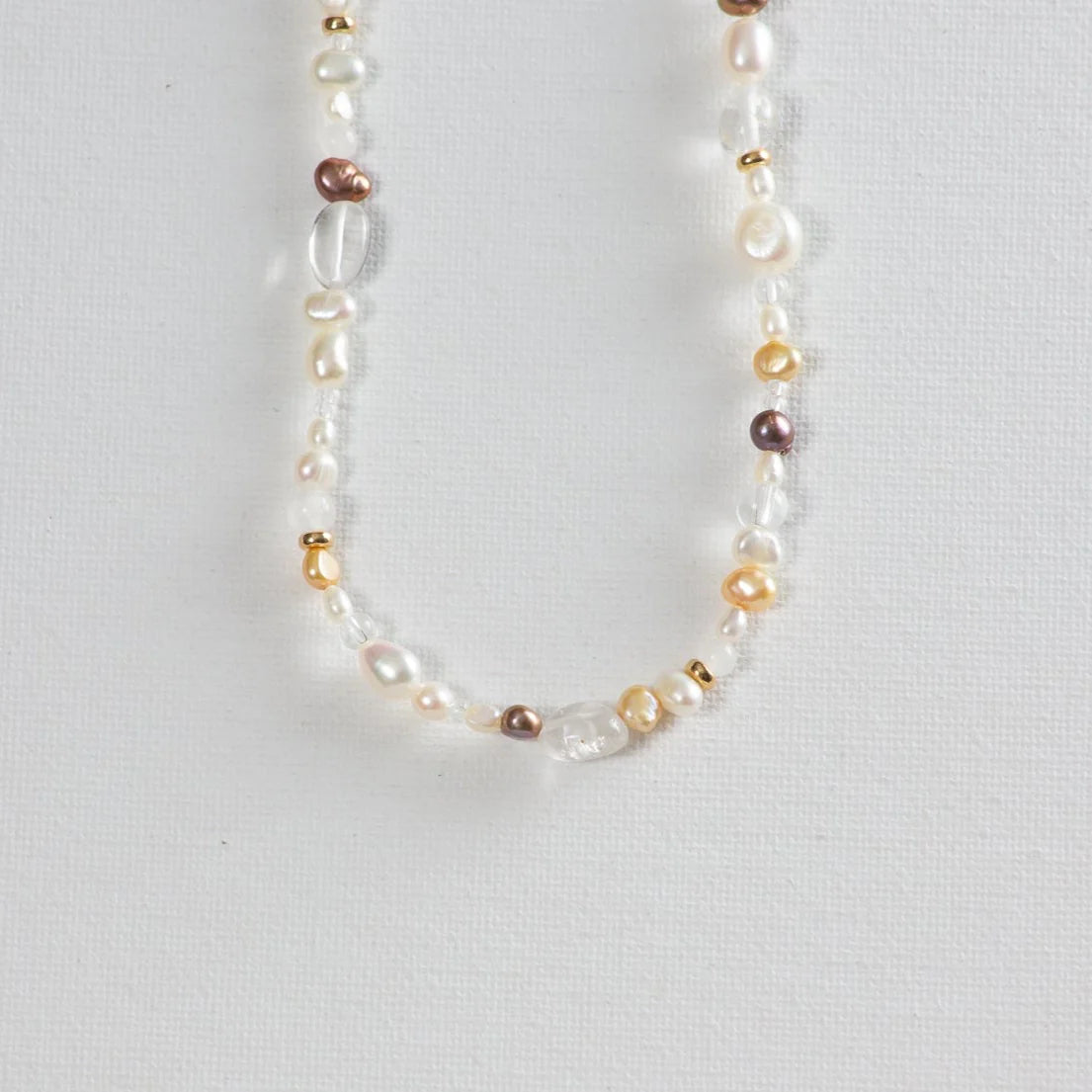 Multi-colored freshwater pearl and gold bead necklace on white background