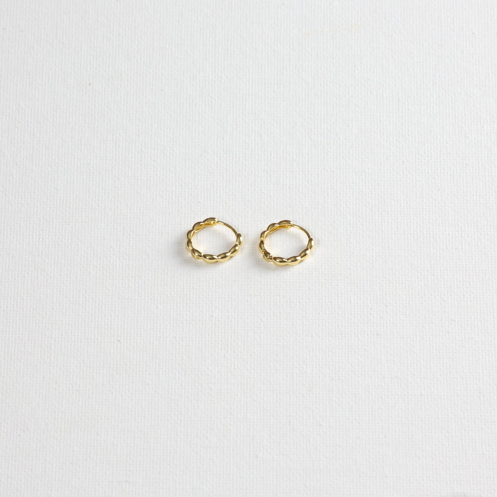 Oryza hoops, gold hoops with rounded textures, photographed on a white background. The photo is taken at a slight angle from the bottom.