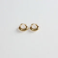 Gold chunky hoop earrings with smooth finish on white textured background