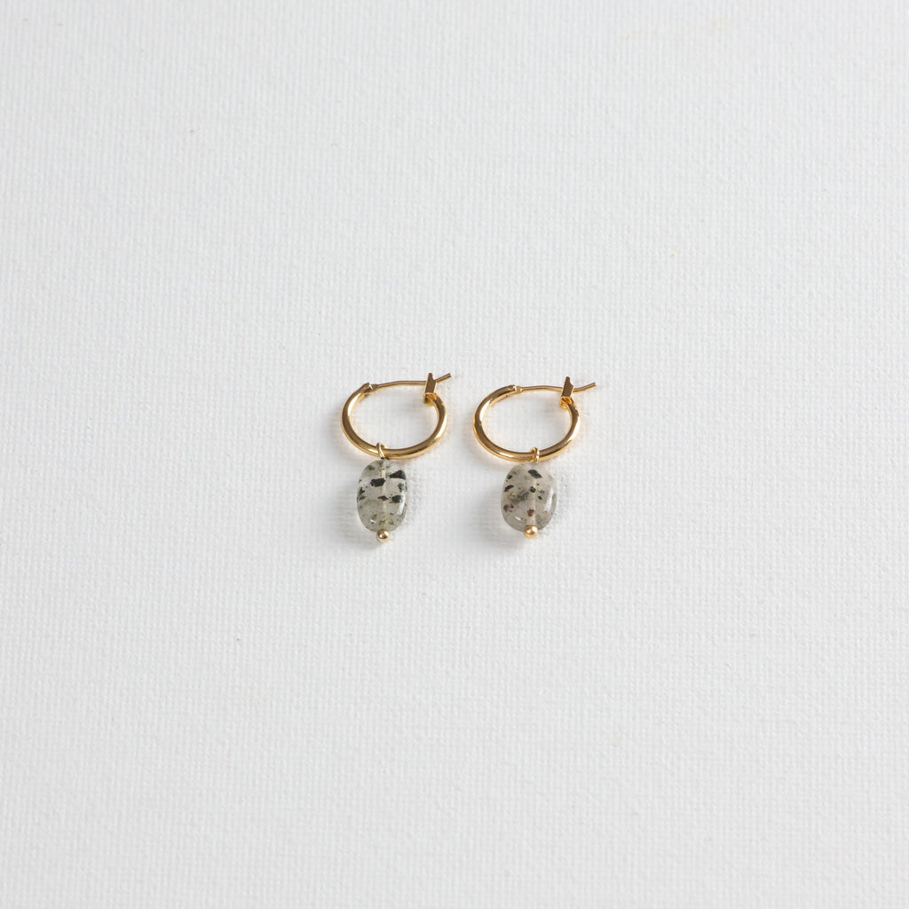 Gold hoop earrings with oval dalmatian jasper stone charms on white background